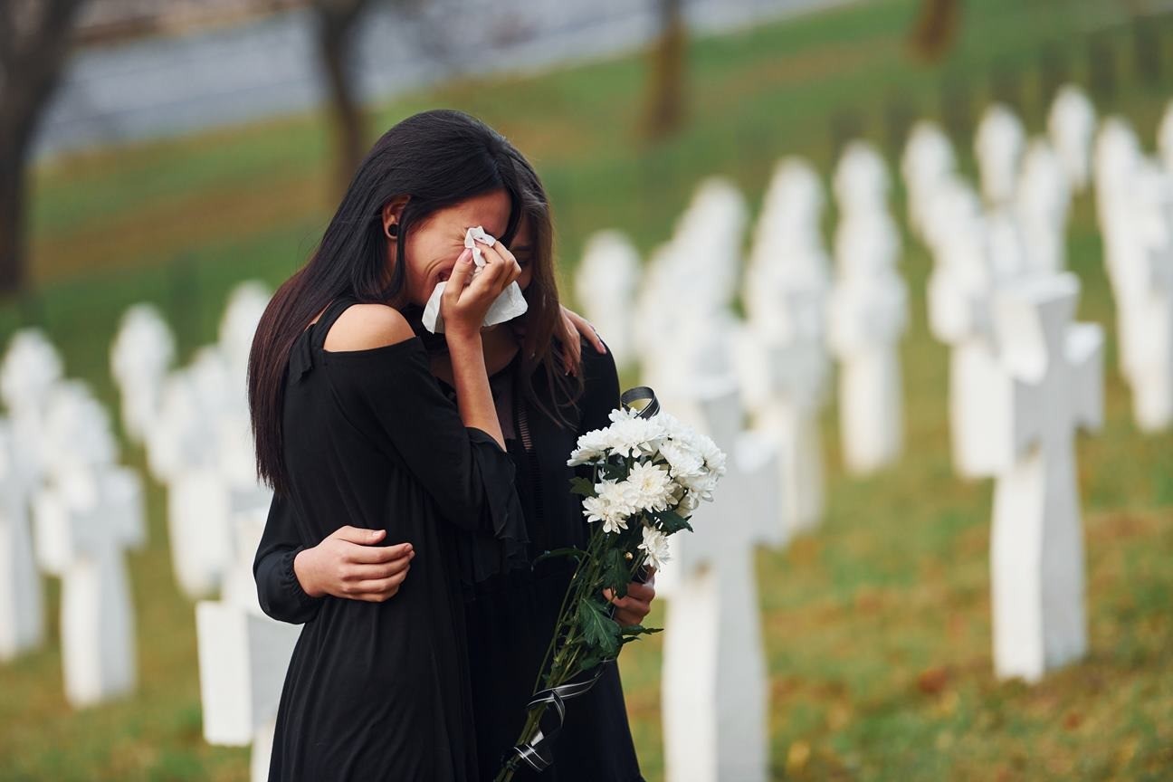 dwie kobiety w żałobie, stojące na cmentarzu